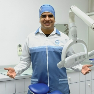 Dr. Alejandro Pena in a blue and white scrubs and blue surgical cap inside a dental clinic